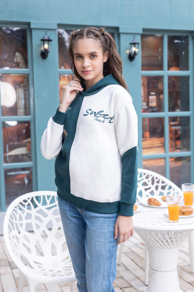 A woman wearing a 2-tone hoodie with elasticated cuff, brand logo and prints in teal color 
