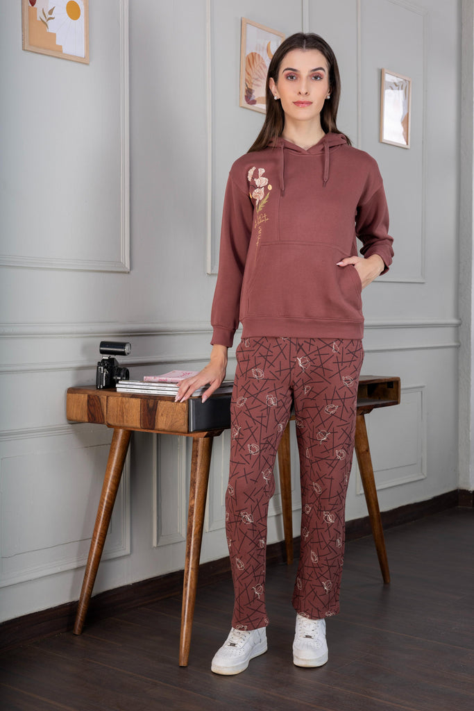 A woman wearing a printed fleece co-ord set with elasticated cuff and hem in rust color.