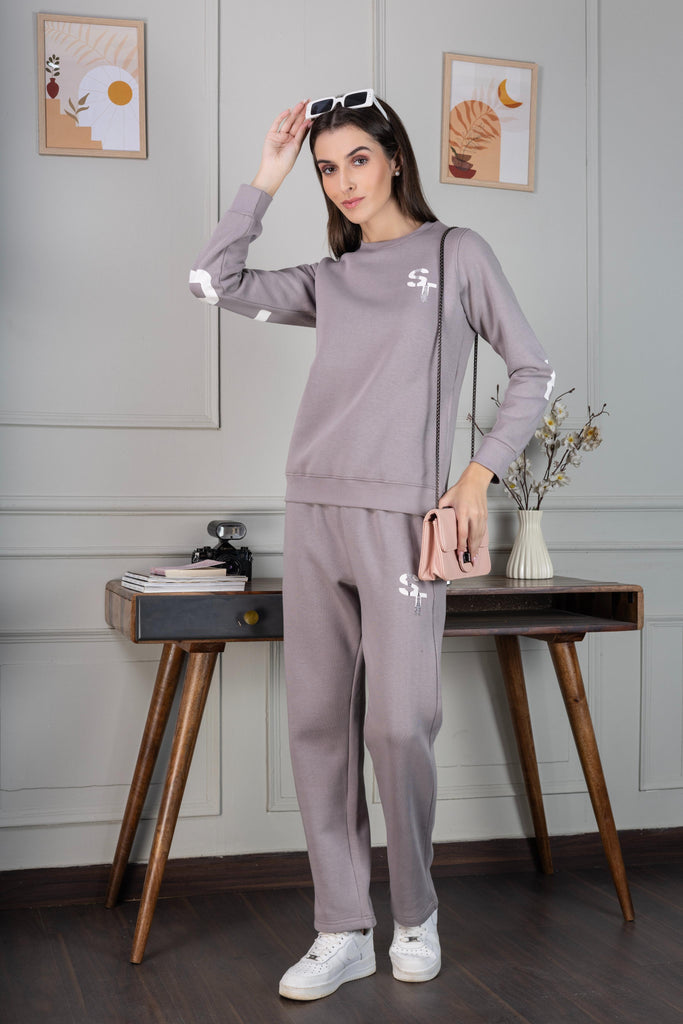 A woman wearing a full sleeve, relaxed fit, fleece co ord set with round neck and back prints in grey  Color 